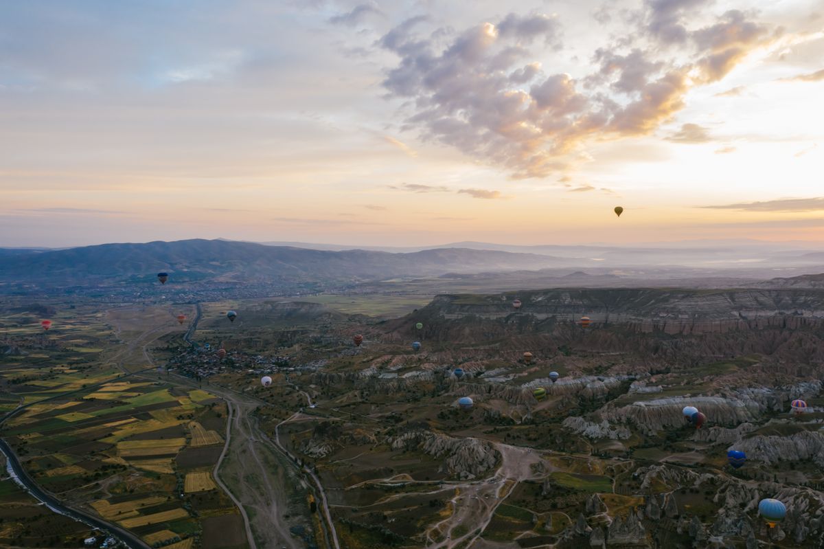 Balon u zraku iznad brežuljaka u zoru